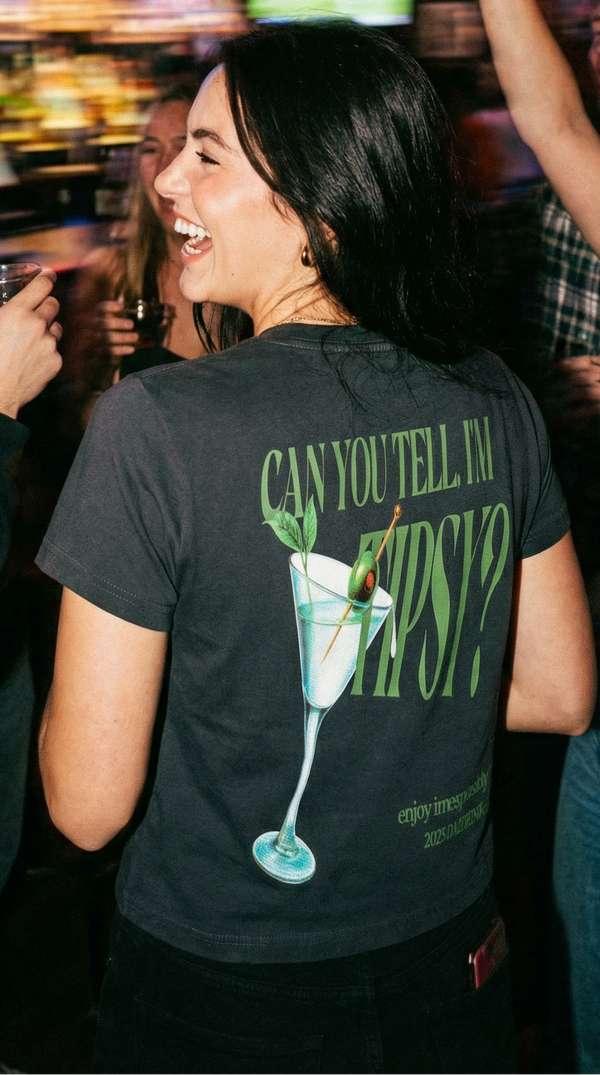 Woman in a bar with friends, wearing a t-shirt with a graphic design.